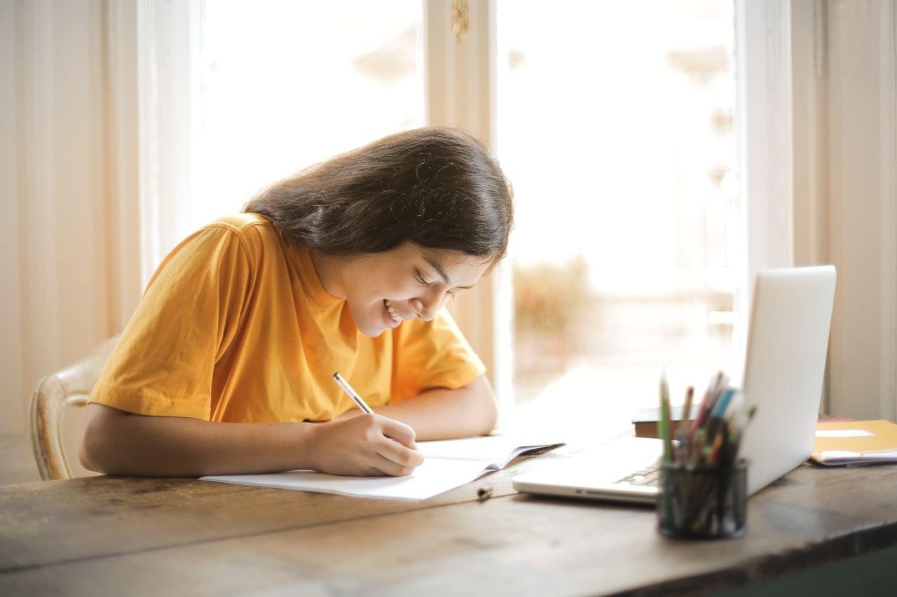 A student writing a personal statement at a desk